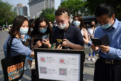 People scan a code to prove their health and travel status before entering a shopping mall in Beijing. AFP