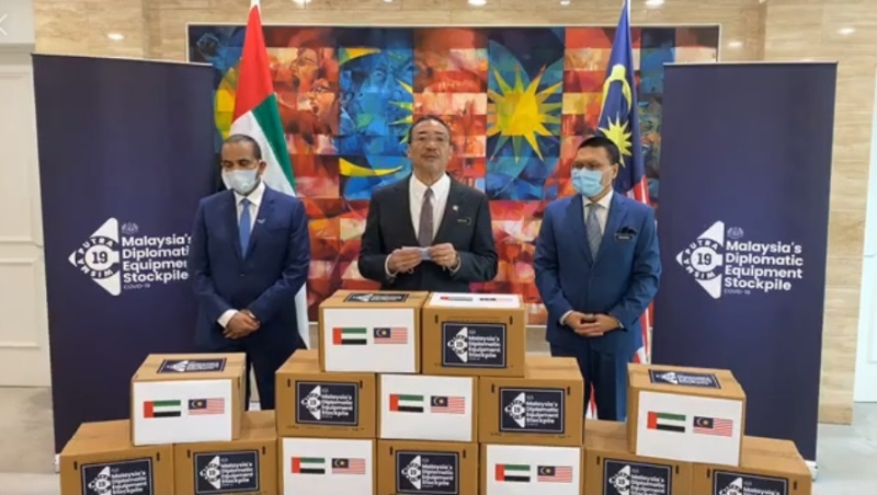 希山（中）见证阿联酋捐献的1万4000支消毒搓手液，并由部门秘书长拿督斯里莫哈末沙鲁（右）负责接领。左为卡立卡宁。

