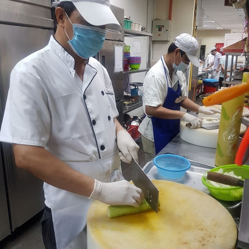 厨师们在煮炒时都保持一定距离,也佩戴口罩和手套。