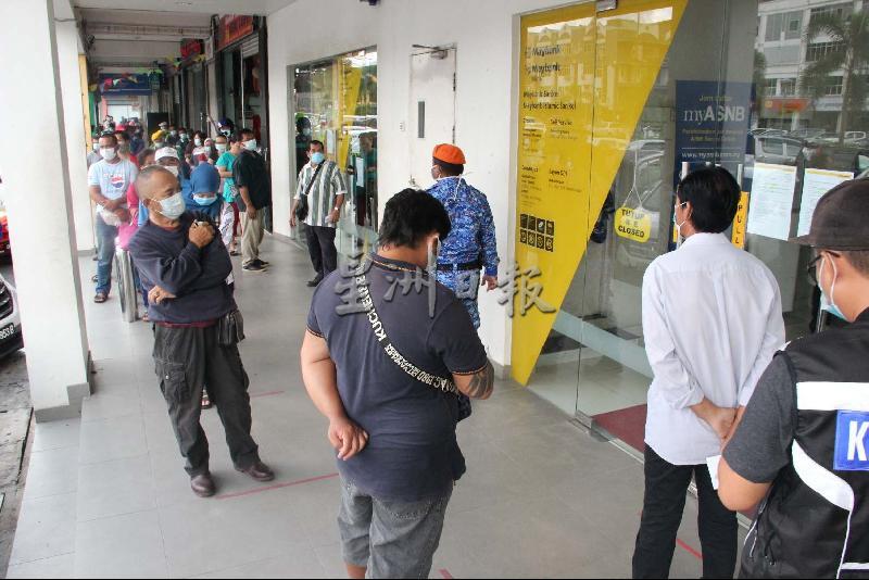 
马来亚银行门外聚集大批人潮。当局出动警察、卫生局官员、县议会执法人员、民防部队及警卫员等到场监督和维持现场秩序。