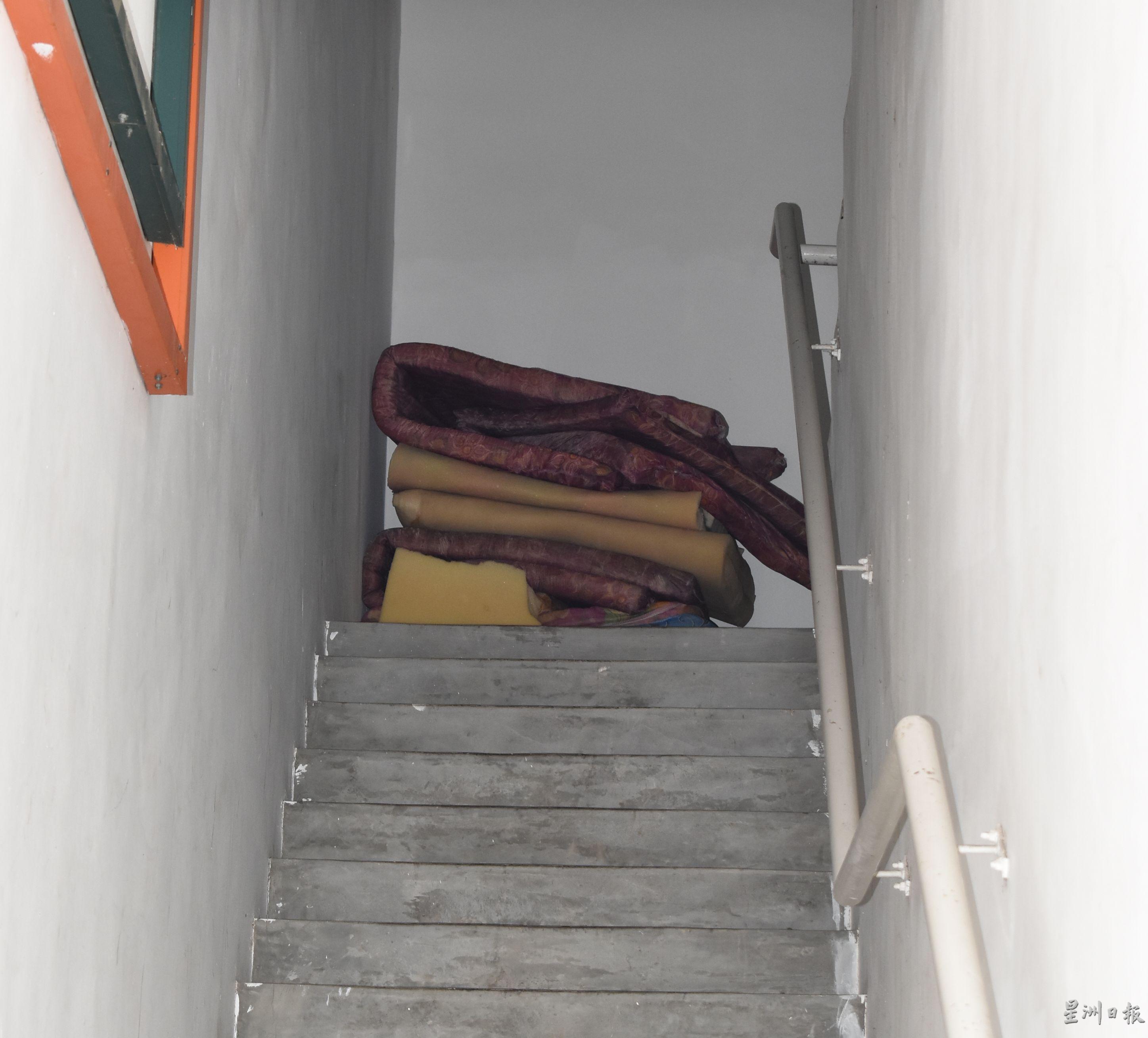 通往楼上外劳宿舍的楼梯间，也堆放许多床褥。