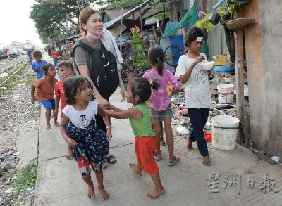 走进贫民窟，吕静霓被学生团团围着，孩子们拉着她的手，渴望获得她的关爱。（摄影/冯依健）