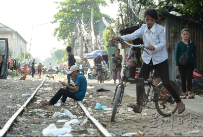 贫民窟社区沿着火车轨道而立，轨道上布满垃圾袋与废弃物。（摄影/冯依健）