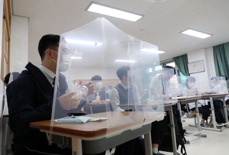 韩国高中三年级学生首先复课，学生的座位都安装防疫隔离板。（图：法新社）