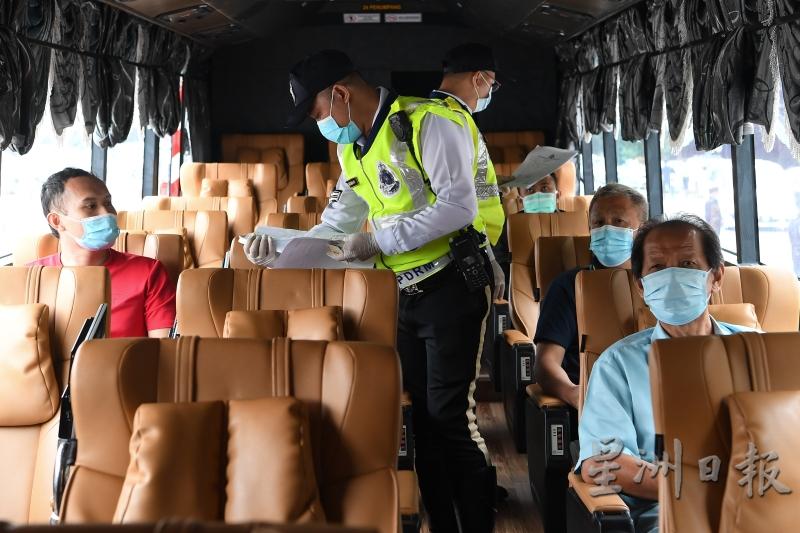 警方在一辆巴士上逐一检查乘客是否拥有跨州批准信函。