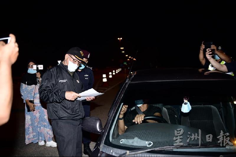 旺依斯迈（左）查看车主是否获得警方批准通行证。