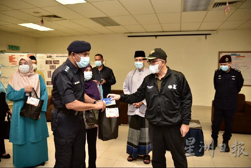 旺依斯迈（右）赠送开斋节物资给前线警员。