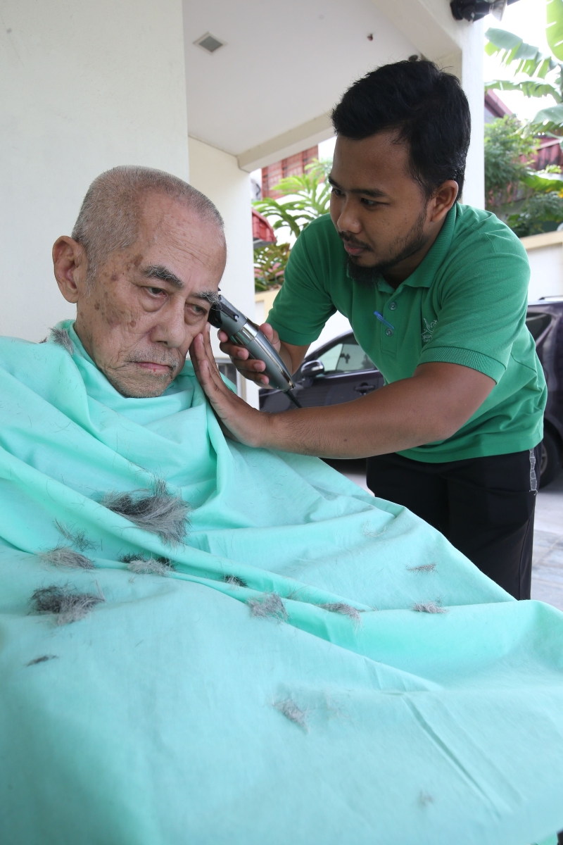养老院的工作人员亲自为一名长者修剪头发。