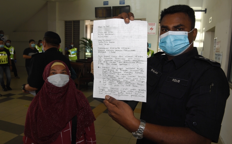 北海警局局长丹纳峇兰出示妇女哈瑟妮（左）自行写的信及获哥打士打县警局的批准，到北海探望儿子。（图：马新社）
