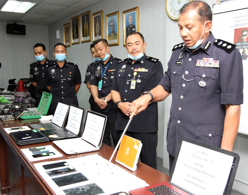 巴哈鲁丁（右一）向现场记者展示所起获的贼赃，包括电脑和手机；右二为蓝赛。