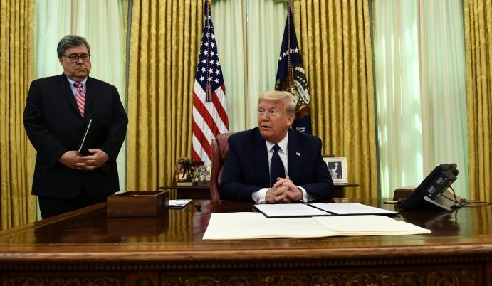 Flanked by Attorney General William Barr, Trump prepares to sign an executive order on social media companies at the Oval Office. AFP
