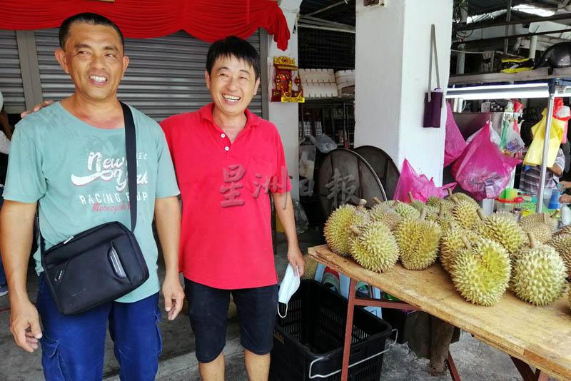 厨业公司生意受影响时，刘德祥（右起）和同事陈炳顺唯有摆摊卖榴梿，共度疫情的难关。