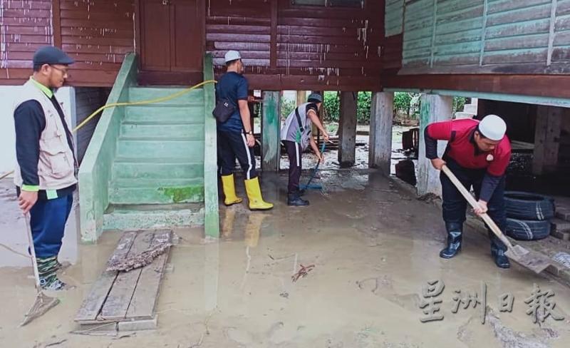 罗斯兰（左）与工作服务队人员协助灾民清洗屋子四周的泥泞。（图：星洲日报）