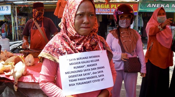 A violator in Bengkulu wearing a sign reading 