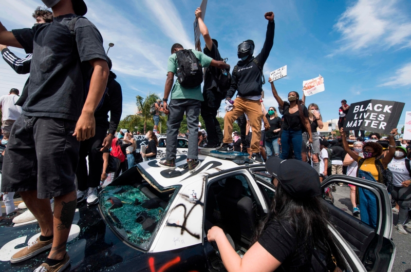 洛杉矶费尔法克斯区示威者砸烂警车，并站在车上欢呼。（图：法新社）