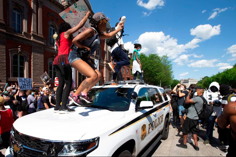 在白宫外抗议的示威者在特勤局的警车上跳。（图：法新社）