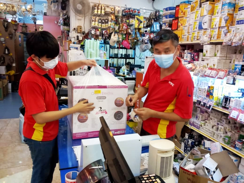 马口WYK电器专卖店开辟网络平台销售电器，巫一强(右)与员工忙碌地把货物包装准备寄出去。
