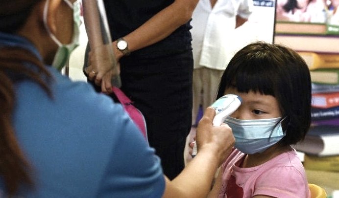 A young pupil has her temperature checked on the first day of school in Singapore. AFP