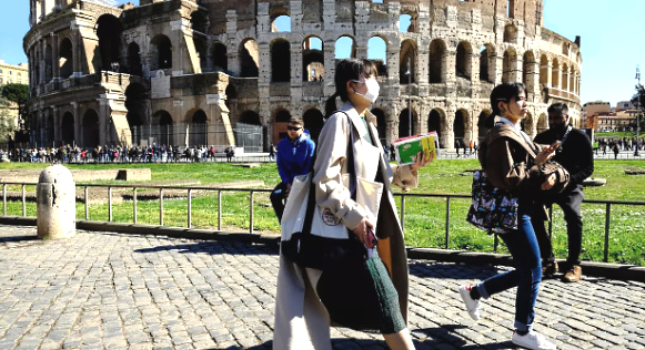 Tourists wearing protective masks tour the Colosseo monument in downtown Rome. AFP