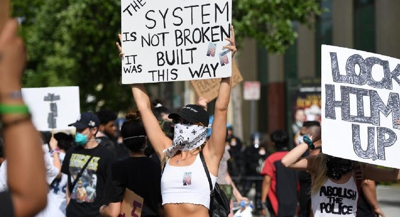 Demonstrators hold signs in front of police in Los Angeles during a protest over the death of George Floyd. AFP