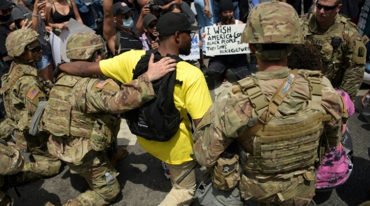 Protesters and members of the Army National Guard kneel together in Los Angeles during a demonstration over the killing of George Floyd. AFP
