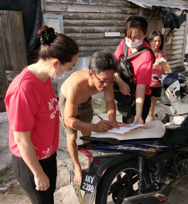 黄嫒香（左）与团队沿户分发捐款，给予十八丁居民。
