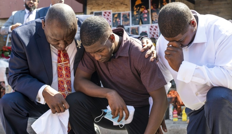 Quincy Mason Floyd (C), son of George Floyd, kneels at the site where his father died in Minneapolis. AFP