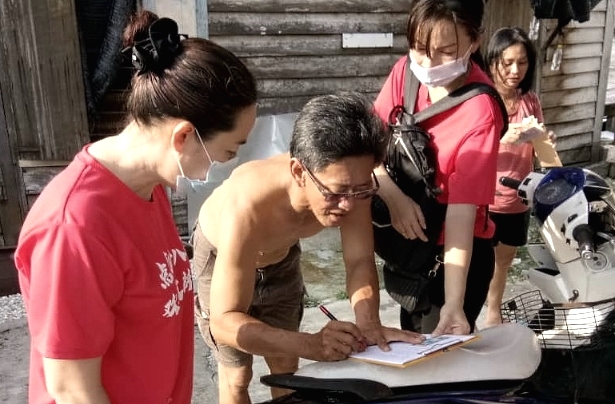 Former village chief Huang (L) and her team distributing the cash donation to villagers. SIN CHEW DAILY