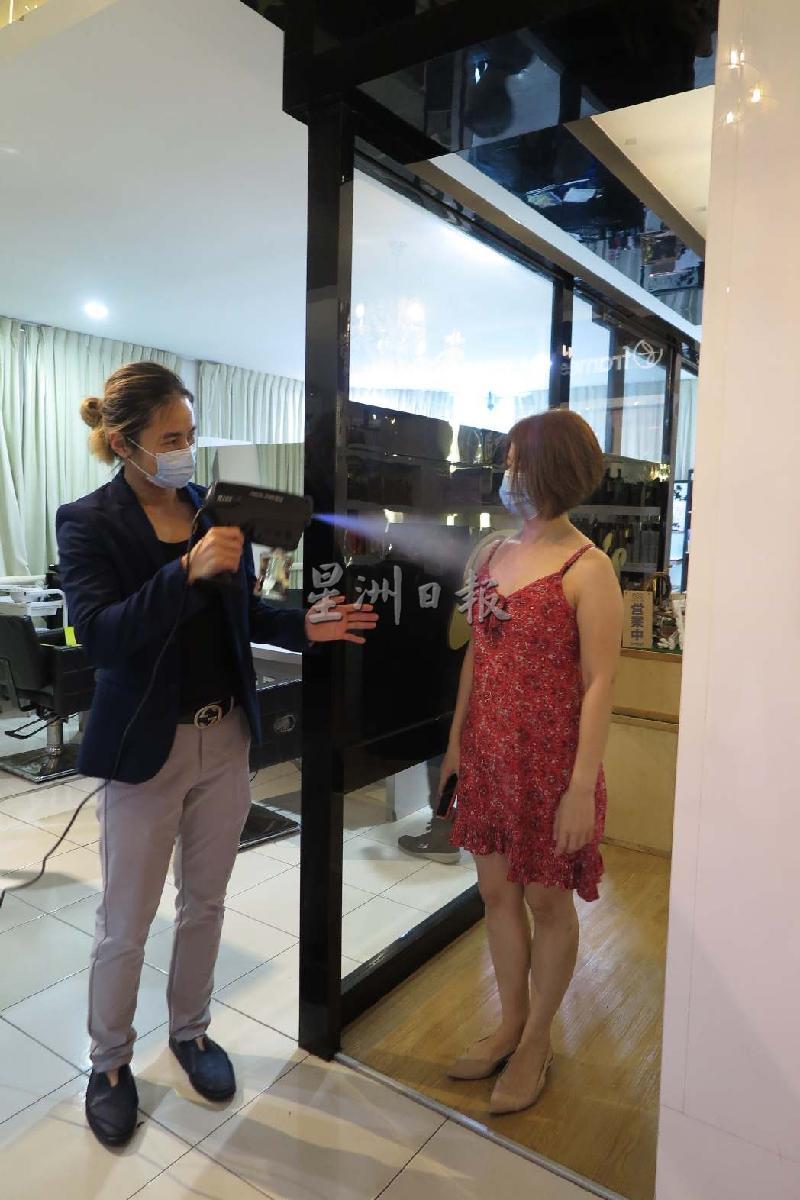 
美发师为顾客全身喷洒消毒喷雾。