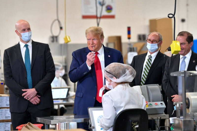 特朗普在缅因州视察一家协助生产冠病测试包中的医疗棉签的医疗工厂，期间拿起一支棉签假装进行测试。