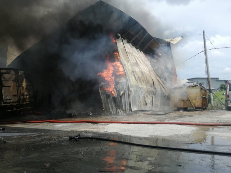 锌板建造的板厂在大火和浓烟中坍塌。
