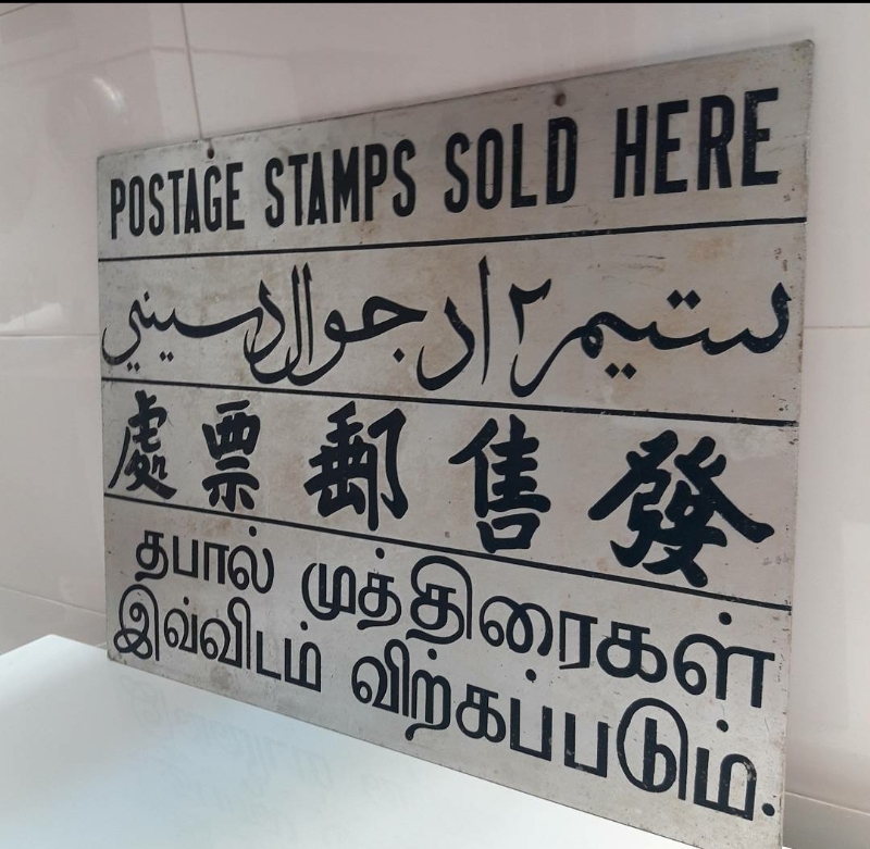 发售邮票的广告牌，附有四种语文，字迹依然清晰。