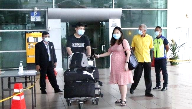 Li Qi Qiang (L2) and his wife are waiting to board a bus at the Miri airport to the quarantine center. Second from right is Datuk Sebastian Ting. SIN CHEW DAILY