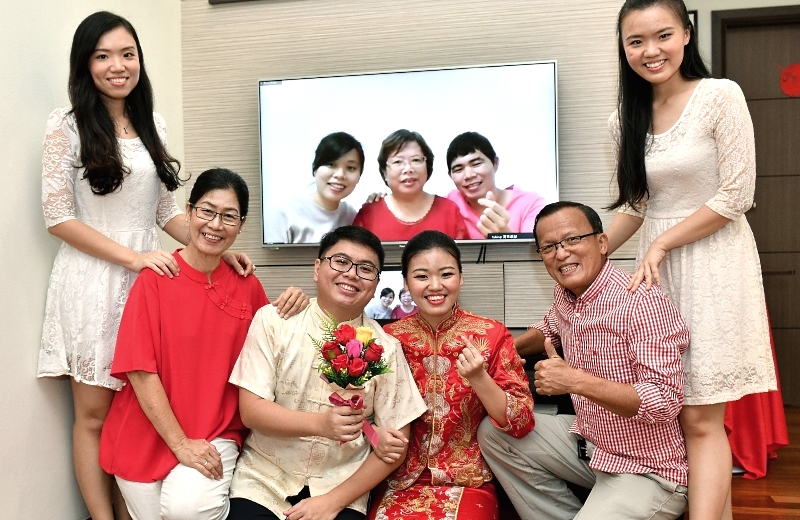 The newly-weds and their parents pose for a family photo in front of the computer screen. SIN CHEW DAILY