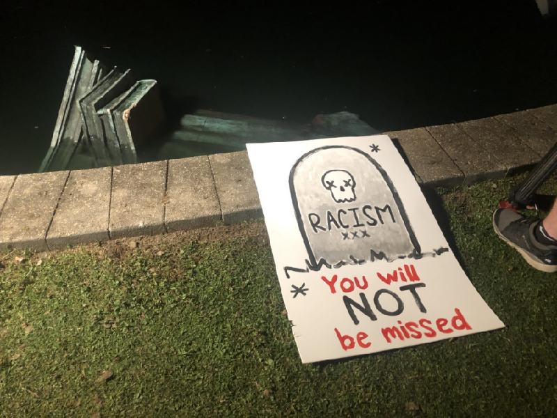 里士满一个公园的哥伦布像被示威推倒丢入湖中，示威者现场留下牌子，写著“种族主义，你不会被怀念”。（图：互联照）