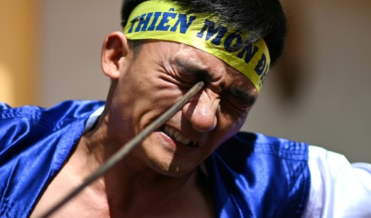 Le Van Thang, 28, student of the centuries-old martial art of Thien Mon Dao, bends a construction rebar against his eye socket inside the Bach Linh temple compound at Du Xa Thuong village in Hanoi. AFP