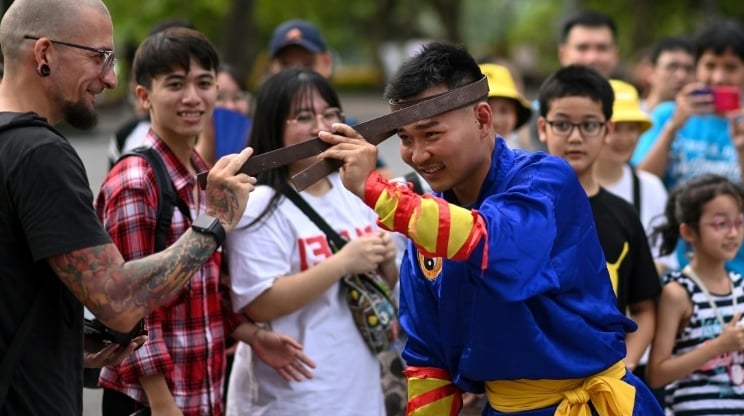 A spectator touches an iron bar bent around the head of a student of the centuries-old martial art of Thien Mon Dao at the Hoan Kiem lake in Hanoi. AFP