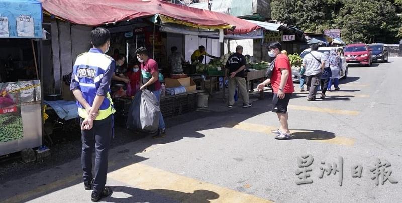执法人员在美兰村市集驻守并监督商家收拾货品和关店离开。