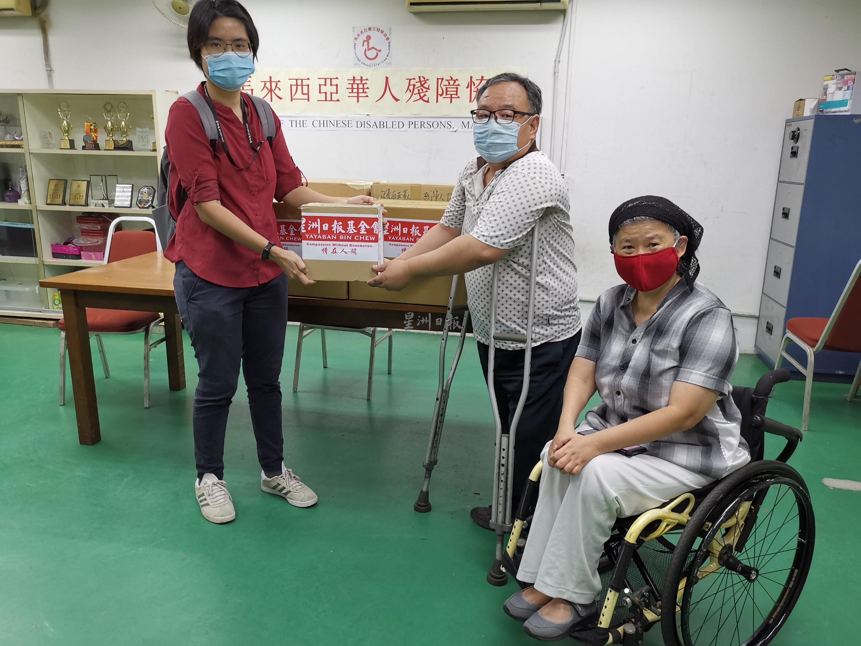 星洲日报基金会代表陈彩珠（左）移交防护用品予马来西亚华人残障协会会长吴爱平（中），谢秀贞（坐者）见证。