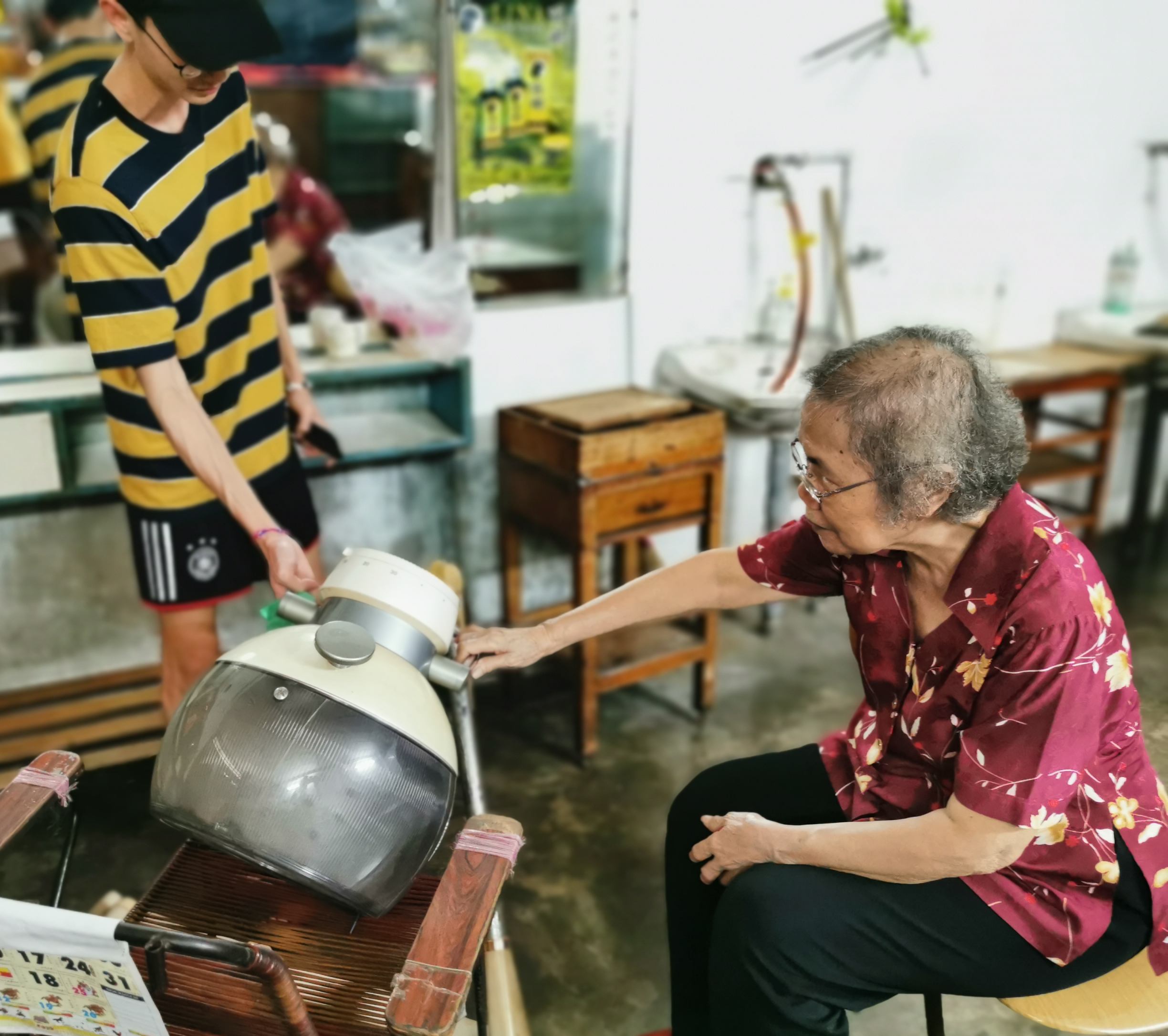吴进凤与孙子察看刚拆下来的古早头发风乾机。
