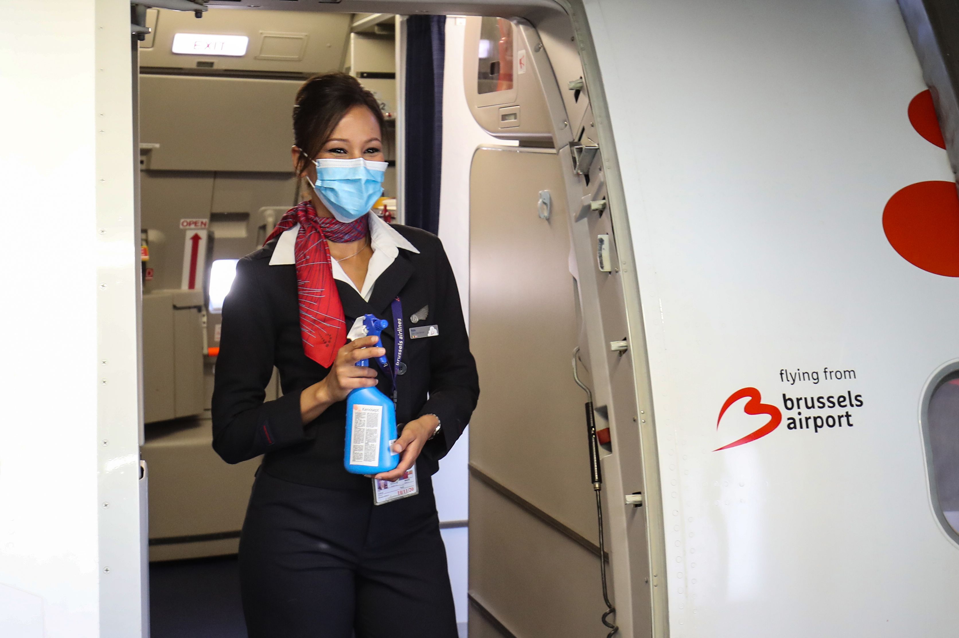 比利时首都的机场周一重新启动，布鲁塞尔航空的空姐戴着口罩，并手持消毒喷雾站在飞机入口处，准备迎客。（图：法新社）