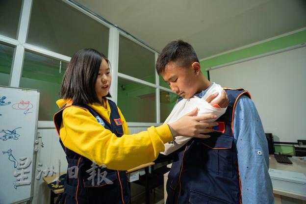 儿童救援俱乐部会员在示范所学到的包扎受伤手部急救法。（图：大马世界宣明会）