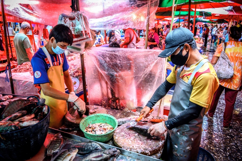 泰国孔堤集市Khlong Toei Market，鱼贩正清理鱼身,员工都穿上“防护衣”和口罩。（图：法新社）