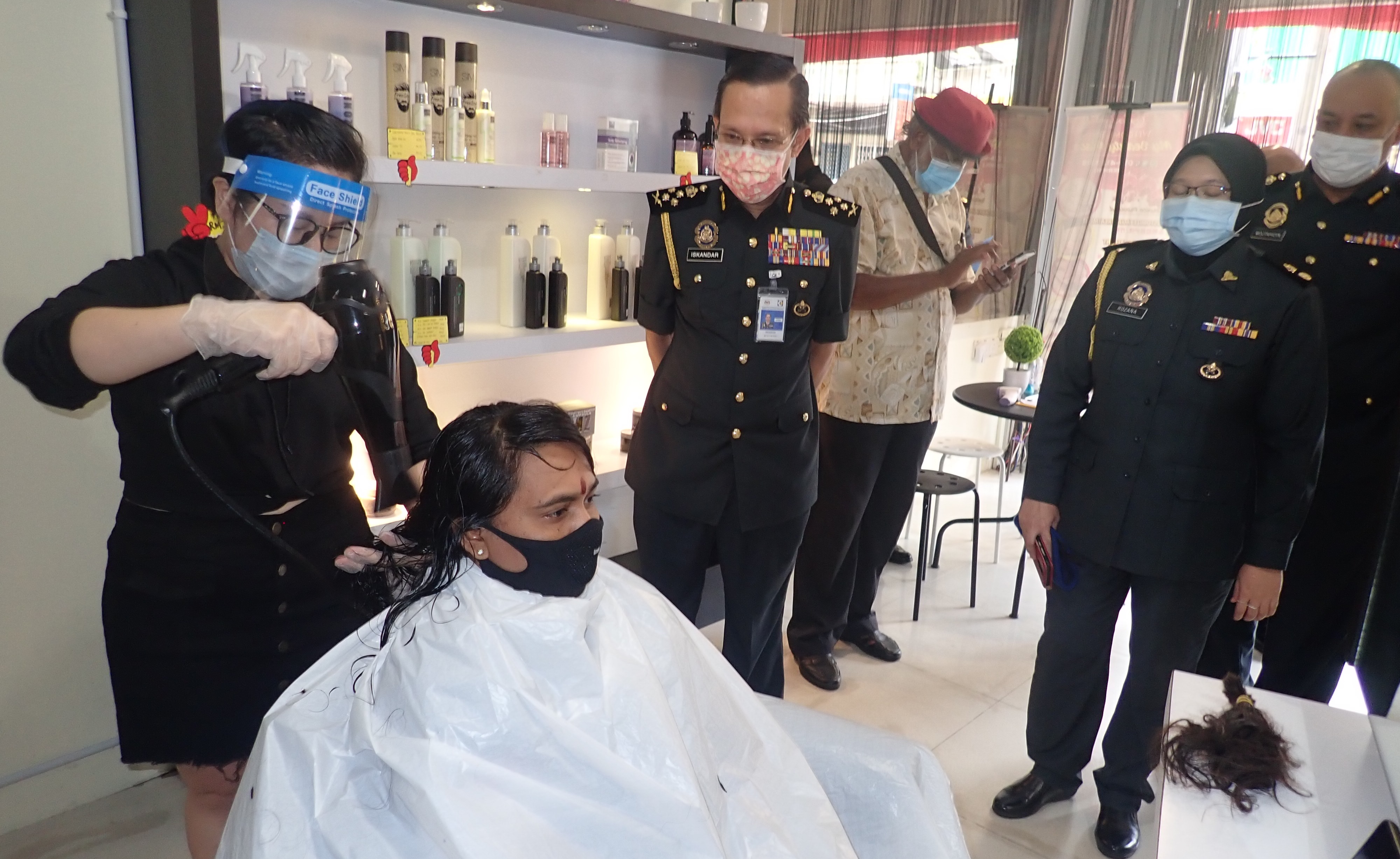 依斯干达（左二）视察美发师为顾客理发。