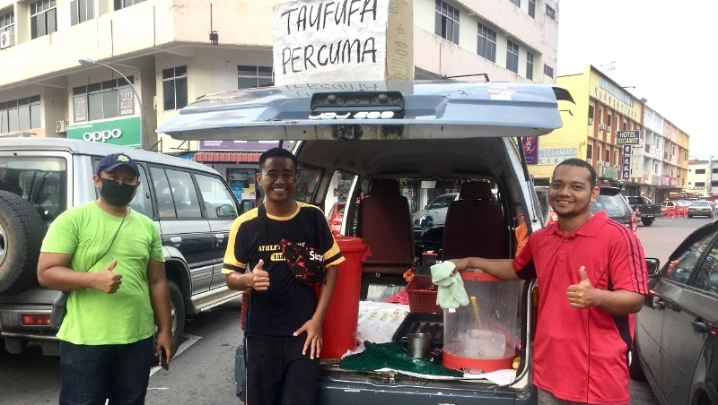 Assisted by two friends, Nazmuddin (R1) distributes free soya milk and tau fu fa to the public. SIN CHEW DAILY