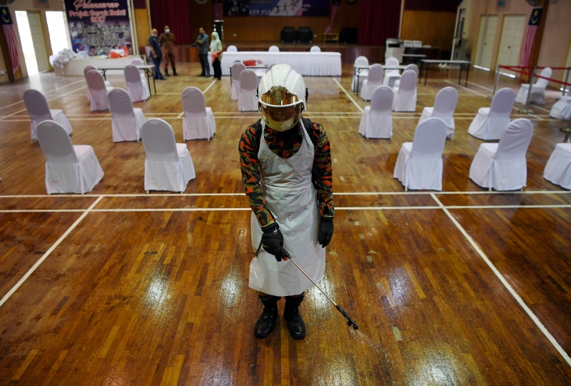 莫哈末阿里夫穿戴好一切防疫配备后，在礼堂执行消毒工作。