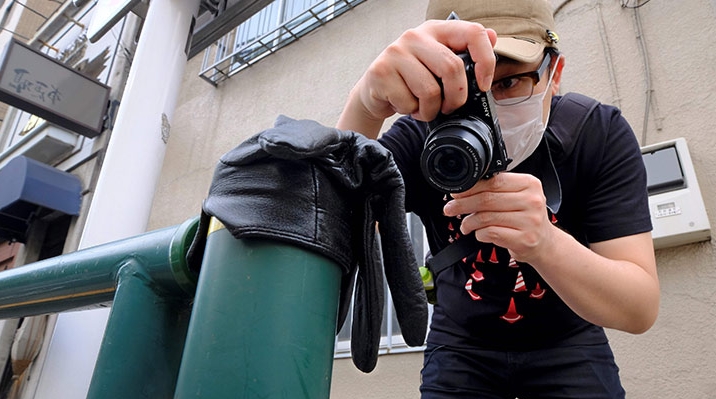 Koji Ishii taking pictures of a lost glove on a pole beside the road in Tokyo. AFP
