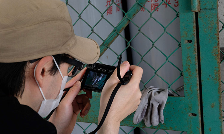Koji Ishii taking pictures of a lost globe hung on a wire fence in Tokyo. AFP