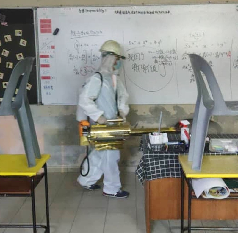 北马日新独中校工在课室内喷消毒液，确保师生在一个安全的环境下上课。