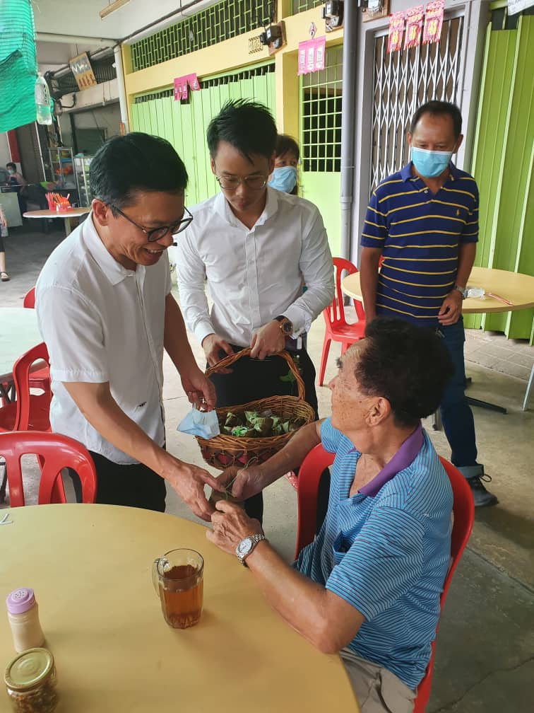 郑联科（左）分派粽子给当地村民，一起分享端午佳节。